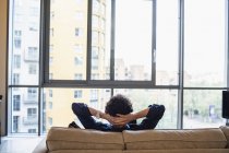 Man relaxing on urban apartment sofa — Stock Photo