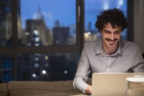 Mann benutzt Laptop nachts in Stadtwohnung — Stockfoto