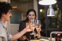 Couple toasting white wine glasses in apartment kitchen — Stock Photo
