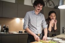 Paar schneidet Gemüse, bereitet Abendessen in Wohnküche zu — Stockfoto