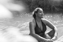Mujer serena sentada en el soleado río - foto de stock