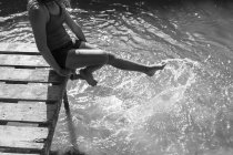 Playful girl splashing feet in sunny river — Stock Photo