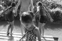 Familia jugando, saltando al soleado río - foto de stock