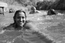 Retrato mujer feliz nadando con la familia en el río soleado - foto de stock