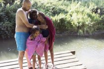 Счастливая семья высыхает после купания на солнечном берегу реки — стоковое фото