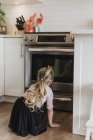 Любопытная девушка смотрит духовку — стоковое фото