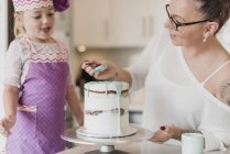 Mother and daughter decorating cake — Stock Photo