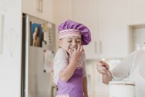 Felice, ragazza carina in cuoco cappello cottura in cucina — Foto stock