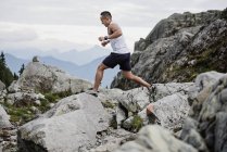 Trekking uomo, salto attraverso rocce, Dog Mountain, BC, Canada — Foto stock