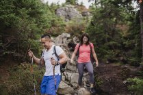 Couple hiking down rocks in woods — Stock Photo