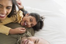 Retrato padres felices e hija abrazándose en la cama - foto de stock