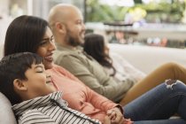 Family watching TV on living room sofa — Stock Photo