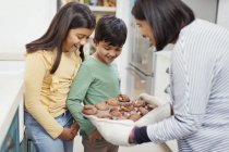 Mother and children baking chocolate muffins — Stock Photo