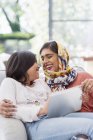 Mãe feliz no hijab usando tablet digital com filha — Fotografia de Stock
