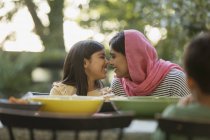 Liebevolle Mutter im Hijab reibt sich am Abendbrottisch die Nase — Stockfoto
