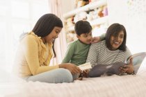 Mother reading book to children on bed — Stock Photo