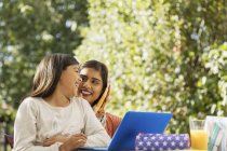 Щаслива мати і дочка використовують ноутбук на патіо — стокове фото