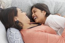 Happy, playful mother and daughter on sofa — Stock Photo