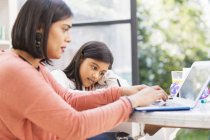 Mother and daughter using laptop, doing homework at table — Stock Photo