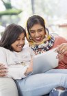 Laughing, happy mother in hijab and daughter using digital tablet — Stock Photo
