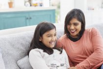 Happy mother and daughter on sofa — Stock Photo