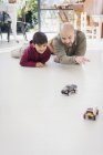 Padre e hijo jugando con coches de juguete en el suelo - foto de stock