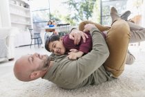 Playful father and son hugging on floor — Stock Photo