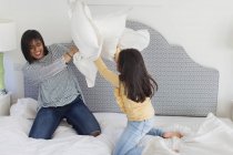 Игривые мать и дочь наслаждаются битвой подушками — стоковое фото