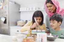 Madre in hijab cottura con i bambini in cucina — Foto stock