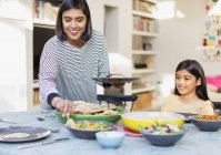Mutter serviert Familie Abendessen am Esstisch — Stockfoto