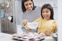Мать и дочь пекут кексы на кухне — стоковое фото