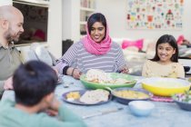Mãe em hijab desfrutando de jantar com a família à mesa — Fotografia de Stock