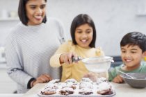 Mãe e crianças assando muffins na cozinha — Fotografia de Stock