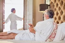 Casal maduro em roupões de banho relaxante no quarto de hotel — Fotografia de Stock