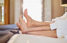Barefoot couple relaxing on hotel bed — Stock Photo