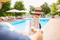 Mature couple holding hands at sunny poolside — Stock Photo