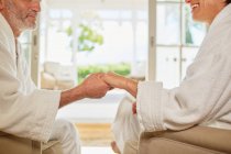 Affectionate couple in spa bathrobes holding hands — Stock Photo
