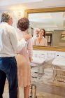 Heureux mature couple debout à hôtel salle de bain miroir — Photo de stock