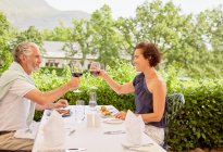 Coppia matura brindare bicchieri di vino al tavolo del ristorante patio — Foto stock
