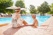 Happy mature couple relaxing at sunny resort swimming pool — Stock Photo