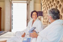 Happy mature couple in bathrobes on bed — Stock Photo