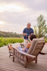 Mature couple relaxing, toasting champagne flutes on resort patio — Stock Photo