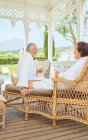 Mature couple in bathrobes relaxing, drinking champagne in resort gazebo — Stock Photo