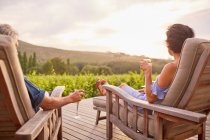 Пара расслабляющих, пьющих шампанское на шезлонгах в солнечном патио курорта — стоковое фото