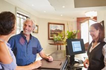 Mature couple checking in at hotel reception — Stock Photo