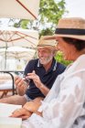 Happy mature couple using smart phone at resort poolside — Stock Photo