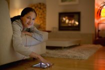 Портрет усміхненої молодої жінки, що слухає музику з навушниками та цифровим планшетом — стокове фото