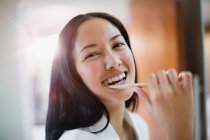 Portrait happy young woman brushing teeth — Stock Photo
