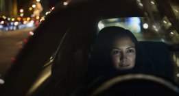 Jeune femme conduisant voiture la nuit — Photo de stock