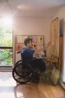 Männlicher Künstler im Rollstuhl malt im Kunstatelier — Stockfoto